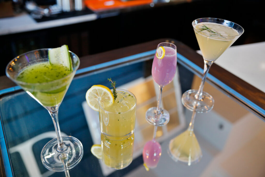 four cocktails laid out on a mirrored bar surface