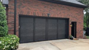Minimalist matte black double garage door with clean horizontal lines installed under a red brick archway.