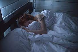 a healthy adult woman sleeping in a comfortable bed in the dark