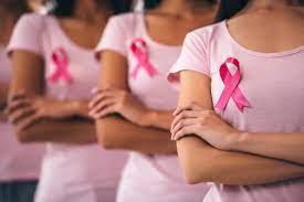 three women with pink shirts and pink ribbons symbolizing breast cancer awareness