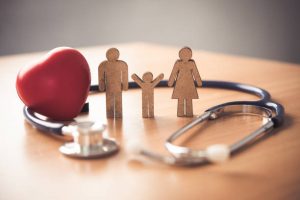 a wooden family on top of a desk surrounded by a stethoscope