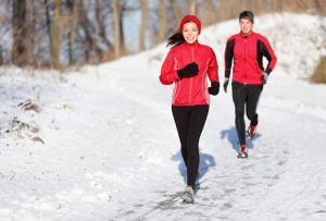 a woman and man running outside in the winter during the holidays