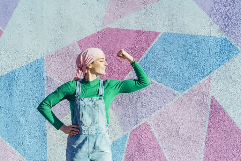 A woman with a bandana on her hair, flexing her arm to show strength.
