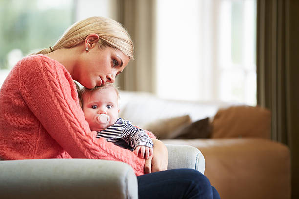 a closeup of a woman and her baby postpartum, with the woman showing signs of sadness.