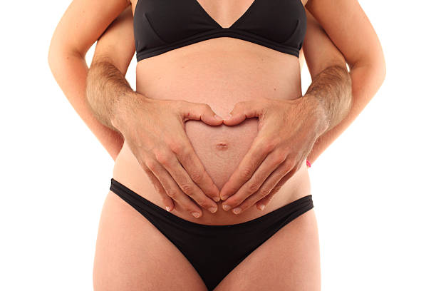 a pregnant woman standing in front of her partner