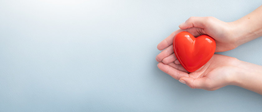 a person holding a red heart on a blue background 