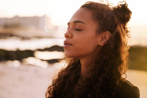 a smiling woman breathing and taking a moment for self care, an important part of maintaining good mental health. 